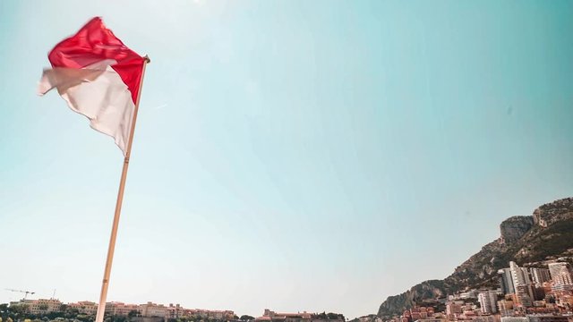 Monaco flag fluttering and Monte Carlo reveal shot on a sunny day