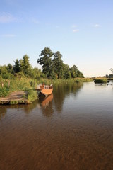 Zachód słońca nad rzeką, łódź zacumowana przy pomoście