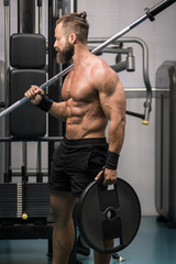 Hombre fuerte con grandes músculos preparando peso para entrenar en el gimnasio. Ponerse en forma.
