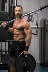 Fototapeta na wymiar Hombre fuerte con grandes músculos preparando peso para entrenar en el gimnasio. Ponerse en forma.