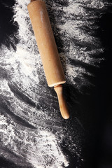 Baking background with the rolling pin with flour. On the dark table. Free space for text