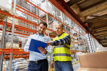 wholesale, logistic business and people concept - manual worker and businessman with clipboards at...