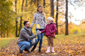 Fototapeta premium family, season and people concept - happy mother, father and little daughter with maple leaf at autumn park