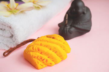 Beautiful orange handmade soap and towel with Orchid flowers for Spa treatments on two-tone background. Incense stick.