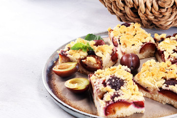 Rustic plum cake on wooden background with plums around.