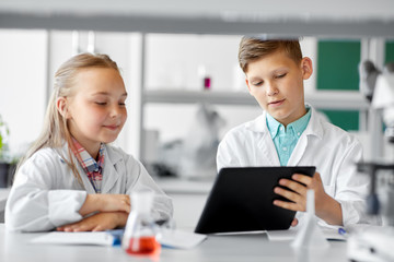 Obraz premium education, science and technology concept - kids with tablet pc computer studying chemistry at school laboratory