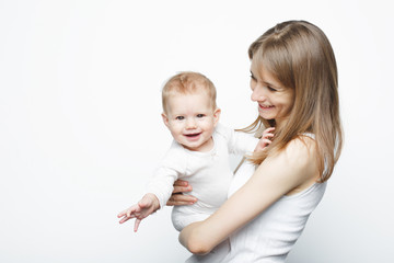 Happy beautiful young mother holding baby girl standing over white background .