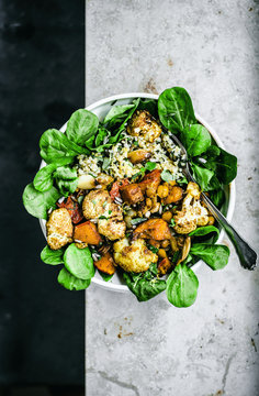 Grain bowl with roasted cauliflower, pumpkin, and chickpeas over lettuce.