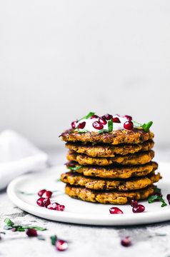 Sweet potato latkes, stacked, with yogurt, herbs, and pomegranate.
