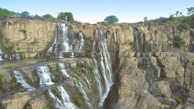 people enjoy waterfall sitting jumping on rocks standing among bushes
