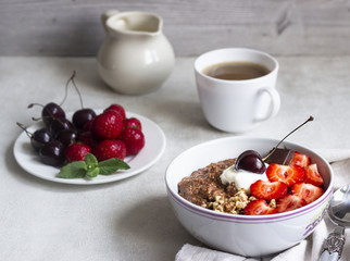 Chocolate oatmeal porridge topped with strawberries, cherries, walnuts and chocolate pieces. The concept of a breakfast. Copy space.