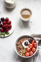 Chocolate oatmeal porridge topped with strawberries, cherries, walnuts and chocolate pieces. The concept of a breakfast. Copy space.