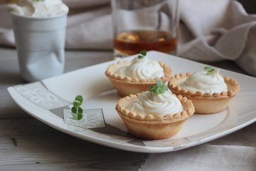 Antipasti tartlets with gentle cheese mousse served with herbs on wooden grey texture background with textile.