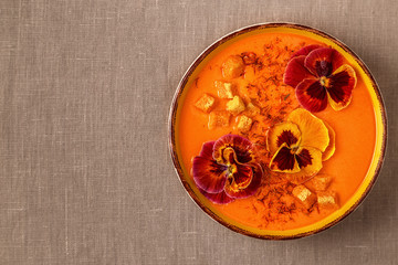 Pumpkin / carrot soup with saffron and edible flowers pansy.