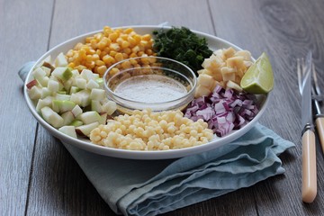 Delicious summer pasta salad on rustic table with corn, apple, red onion, cheese and dill