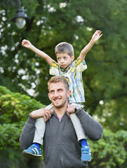 father carrying son on neck