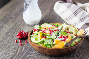 Superfood salad with avocado, tangerines, pomegranate and seeds with yogurt dressing.