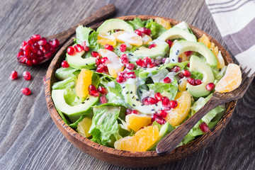 Superfood salad with avocado, tangerines, pomegranate and seeds with yogurt dressing.