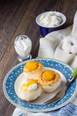Cottage cheese pancakes on a plate with sour cream and orange jam. Syrniki. Traditional Ukrainian and Russian cuisine