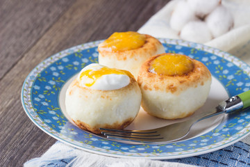 Cottage cheese pancakes on a plate with sour cream and orange jam. Syrniki. Traditional Ukrainian and Russian cuisine