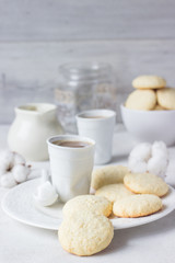 Plate with homemade coconut cookies and a cup of coffee with milk on a light background.