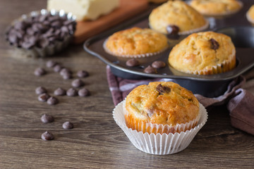 Muffins with chocolate chips (drops) in bakeware (muffin pan) on linen towel. Basic muffin recipe. Homemade muffins for breakfast or dessert.