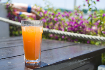glass with orange juice and ice on a wooden table