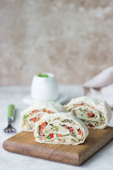 Tuna salad roll sandwich on wooden cutting board. Roll sandwich with tuna, avocado, apples and red bell pepper. Thin Armenian pita bread or lavash. Snack.