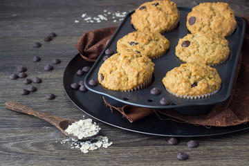 Muffins with chocolate chips (drops) in bakeware (muffin pan) on linen towel. Basic muffin recipe. Homemade muffins for breakfast or dessert.