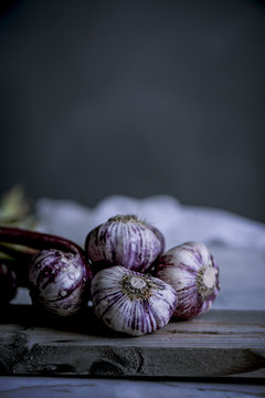 Purple and white garlic bulbs in a rustic kitchen