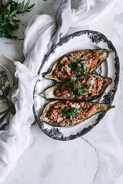A bolognese sauce served in an eggplant shell on a marble background