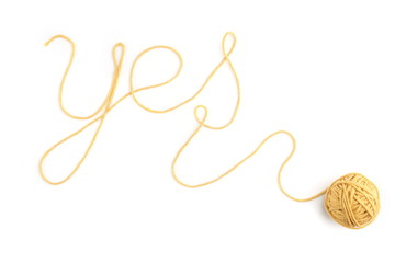Word yes made of yellow thread and thread ball isolated on white background. Cotton thread ball with word yes.