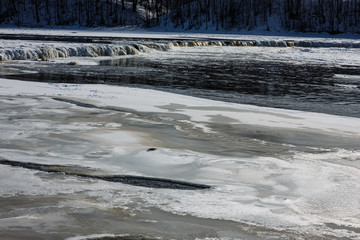 winter landscape on the river; partly a frozen waterfall across the river;