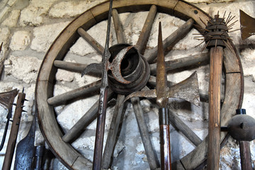 Mittelalterliche Waffen und ein altes Wagenrad an einer steinernen Mauer auf der Wachsenburg
