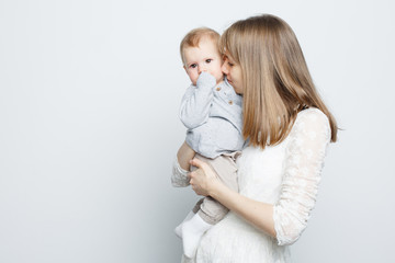 Young mother holding baby girl standing over white background.