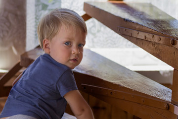 Baby boy crawling up the stairs. Cute toddler looking at camera