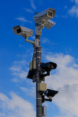 Different types of CCTV security cameras fixed on a pole on a blue sky background - security, big brother concept
