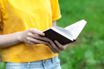 Young female reading book in summer park