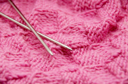 Detail of woven handicraft knit woolen design texture and knitting needle. Fabric pink background