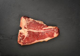 Close up raw beef T-bone steak on slate board