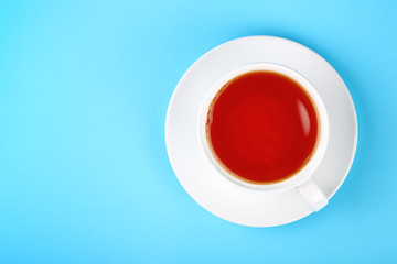 White cup of black or red fruit tea over blue