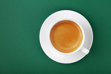 White cup of espresso coffee on saucer on green