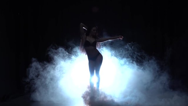 Girl is dancing a sexy dance . Black background. Silhouette. Slow motion