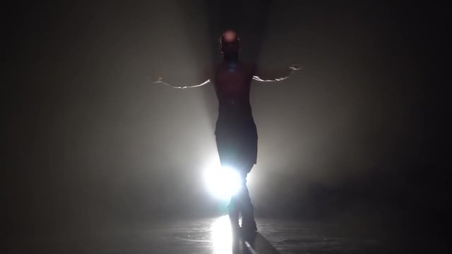 Man is dancing a strip . Black background. Silhouette. Slow motion