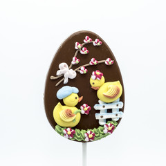 Lecca lecca di cioccolato a forma di uovo decorato con forme di zucchero in tema di Pasqua