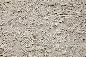Rough plaster wall texture with chaotic semicircular grooves.
