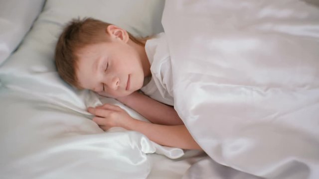 Seven-year-old boy nice sleeping in his bed.