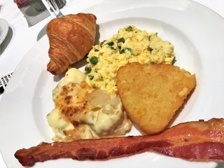 Breakfast meal with hashbrowns, eggs, bacon and croissant