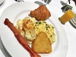 Breakfast meal with hashbrowns, eggs, bacon and croissant