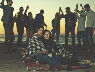 Naklejka premium Couple enjoying with friends at sunset on the beach
